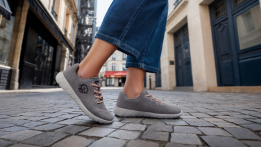 Person wearing jeans and grey trainers walks through a cobbled street in the old town