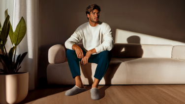 Man in beige slippers sitting relaxed on a beige sofa