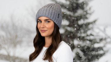 Woman wearing a grey knitted hat in a snowy winter landscape